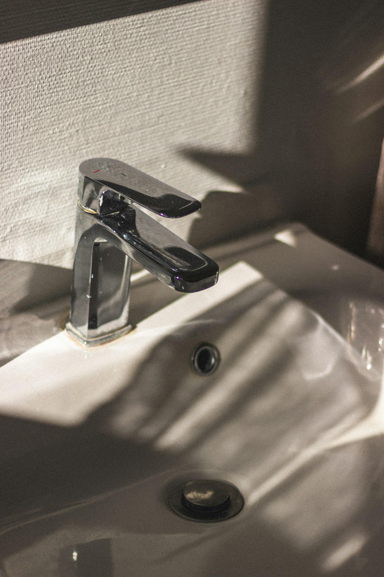 A stainless-steel faucet mounted on a white ceramic sink