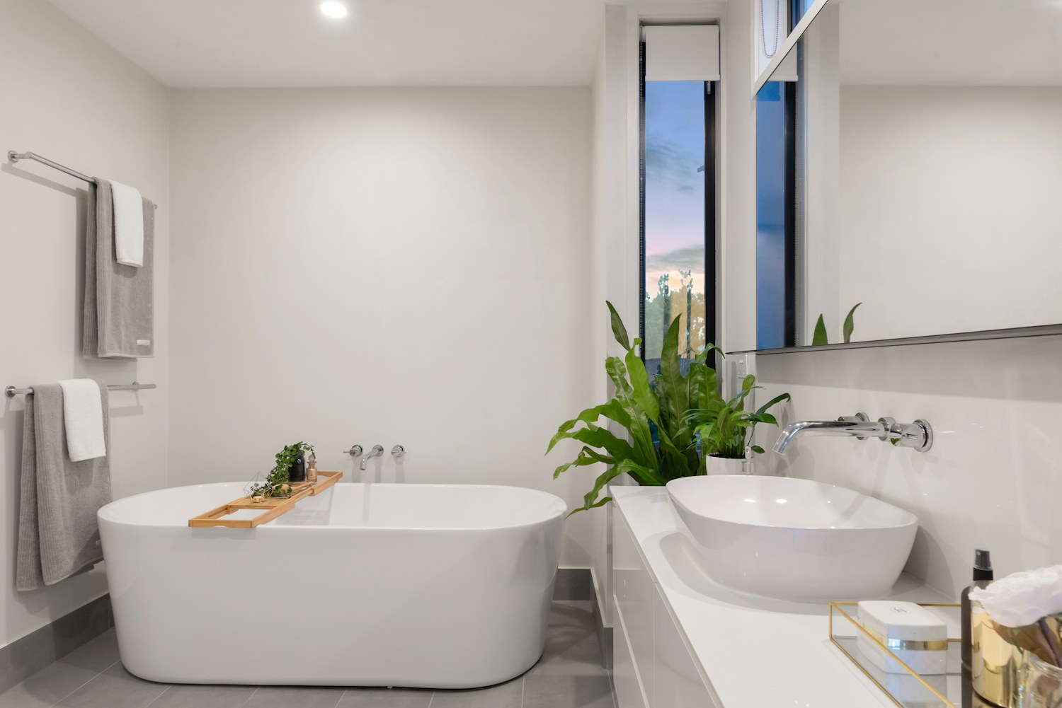 A white bathtub beside a leafy potted plant