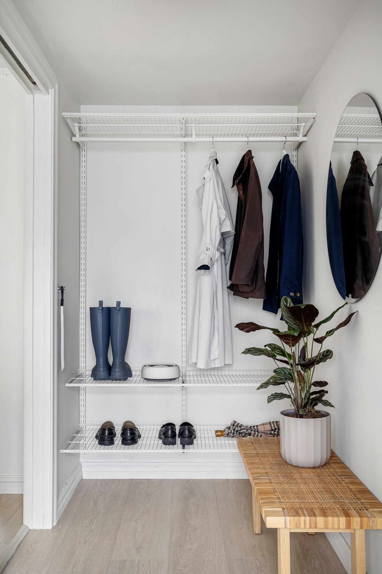 A room with an entryway bench, mirror, and coat rack