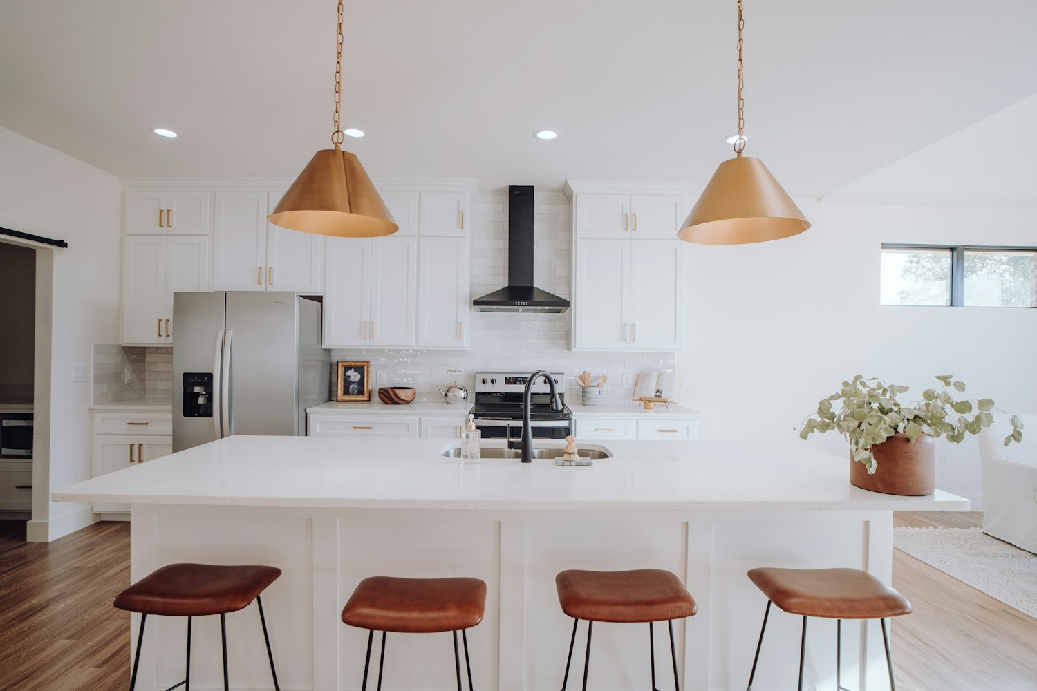 A kitchen island with stools and white cabinetry