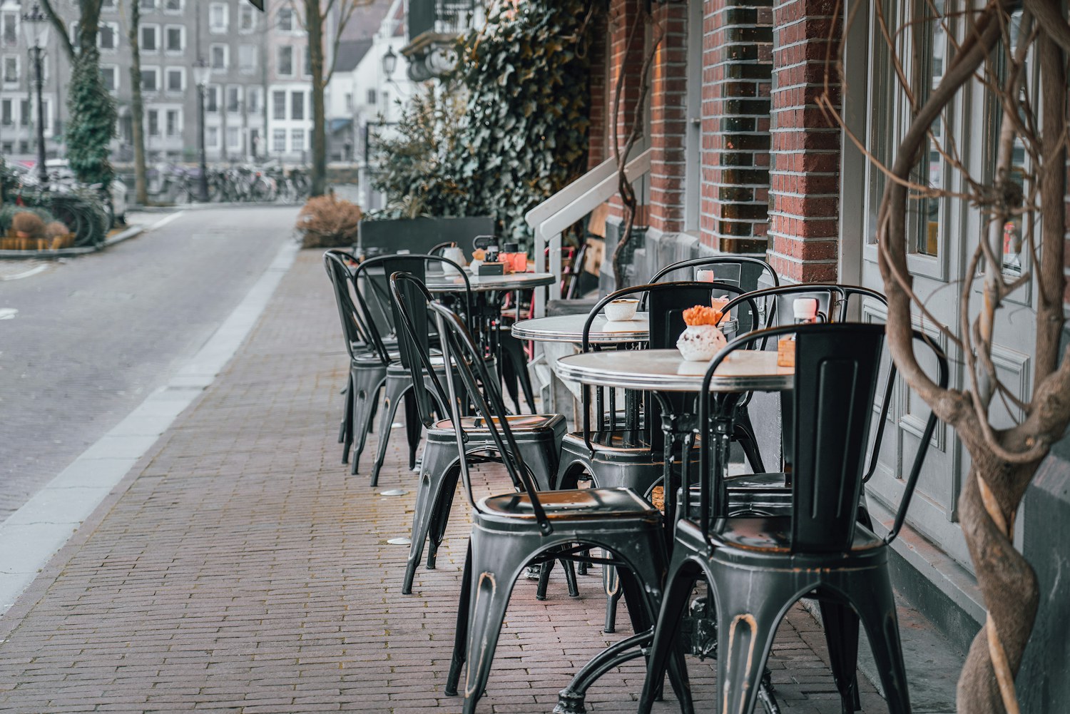 Outdoor tables and chairs arranged along a sidewalk patio