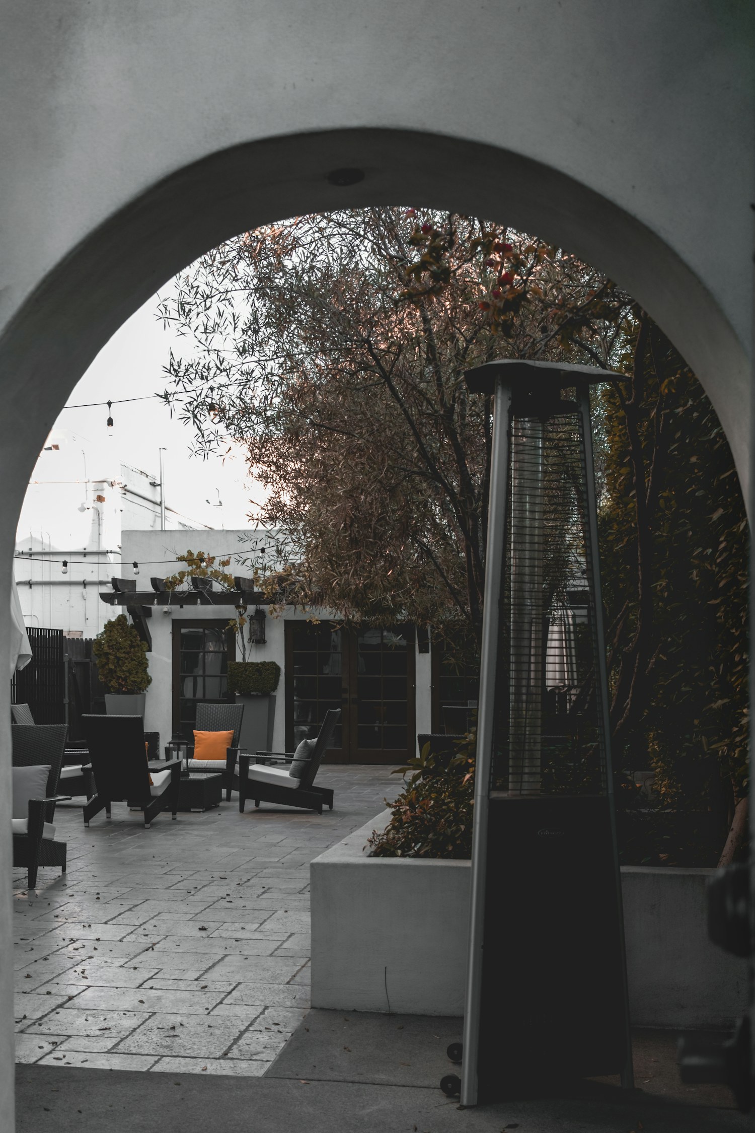An outdoor patio seating area with a heater and trees