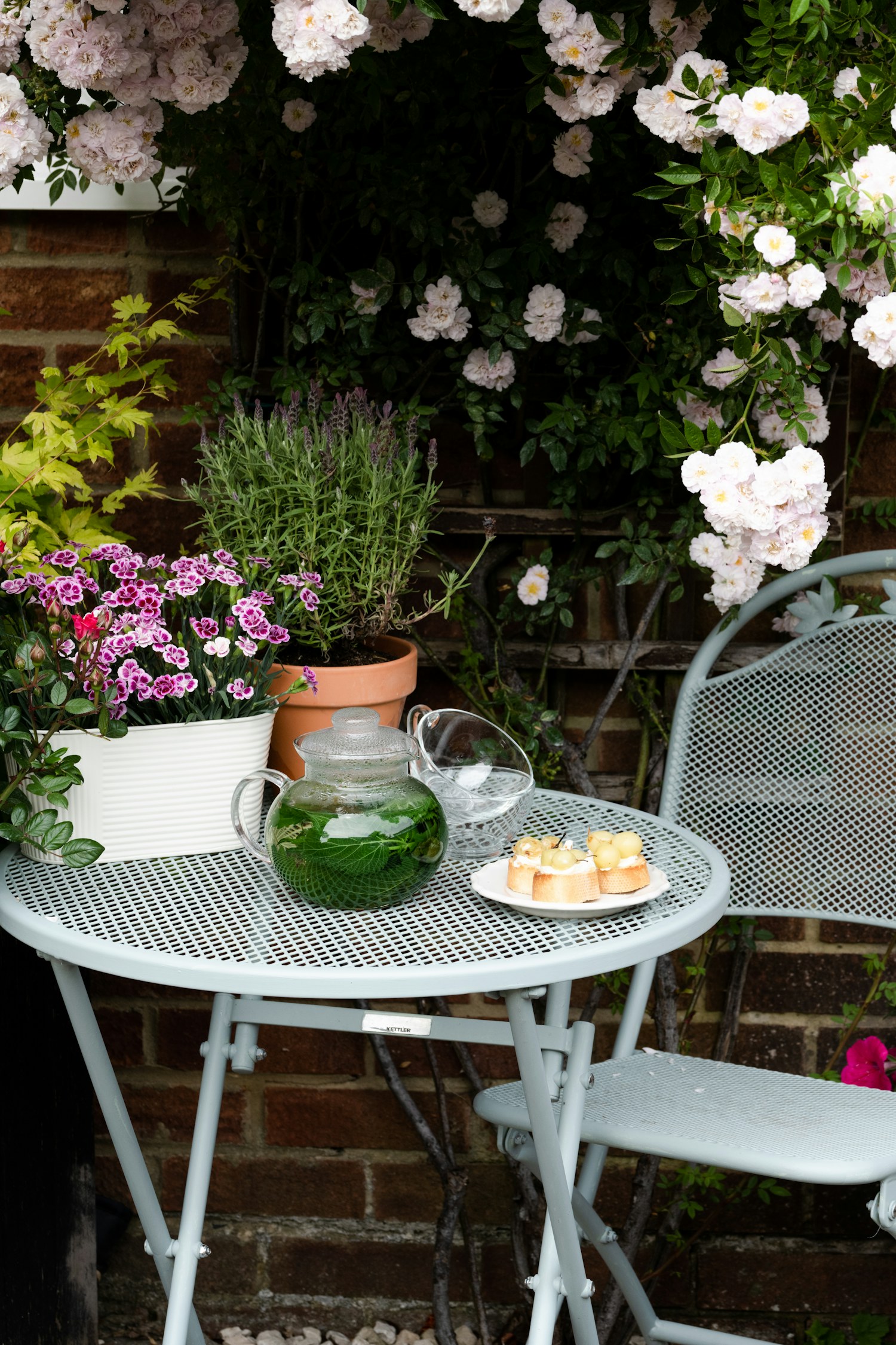 A patio table and chairs near flowering plants
